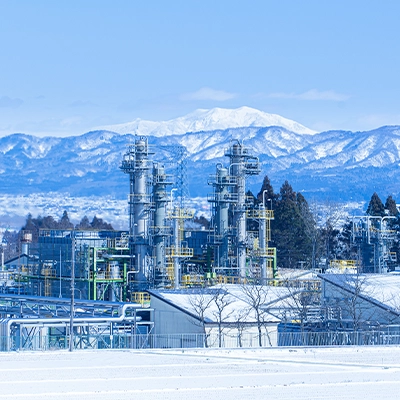 雪景色の中にある石油天然ガス施設で、背景には山々が広がる